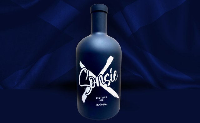 Blue opaque bottle with the word 'Sonsie' in white and a white cross behind. The background is a blue saltire flag.