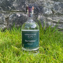Load image into Gallery viewer, Full, clear glass gin bottle with a dark green label and the words &#39;Arrochar Alps The Cobbler&#39;, sitting on a grass with a traditional stone wall behind.
